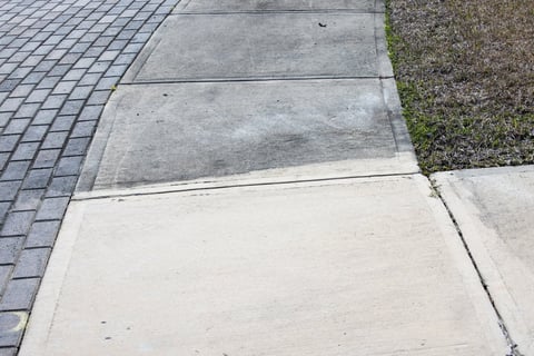 Partially cleaned concrete driveway showing before and after