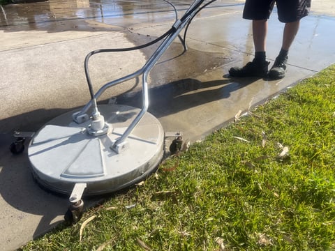Worker pressure washing surface with high-pressure water spray